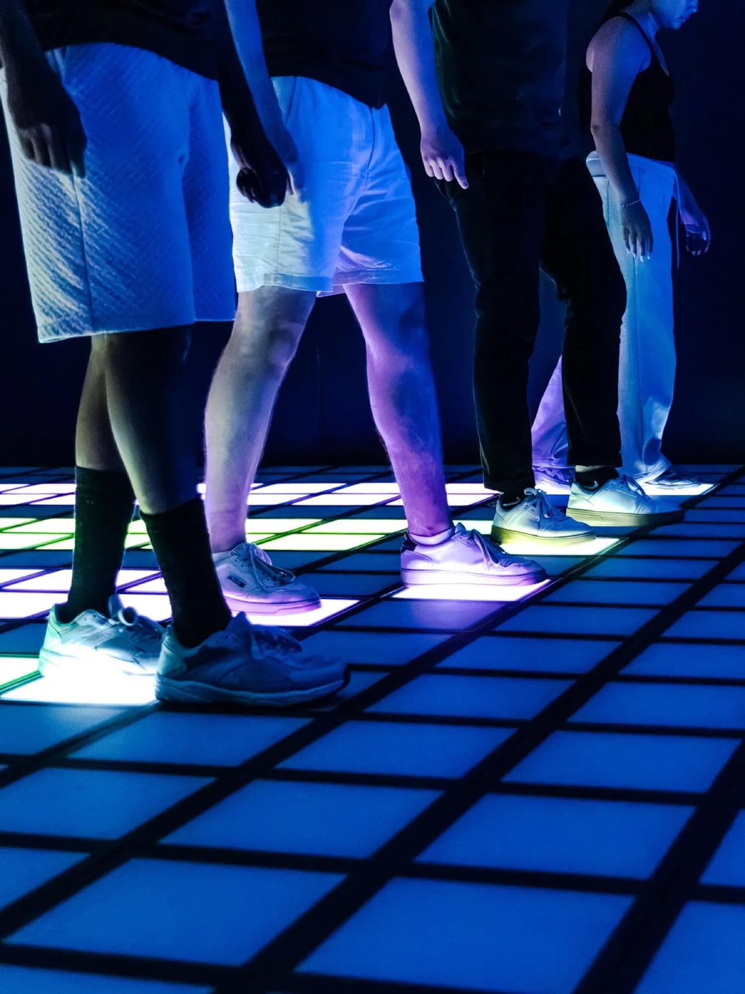 Joueurs sur le sol de dalles lumineuses de la salle PIXEL ROOM