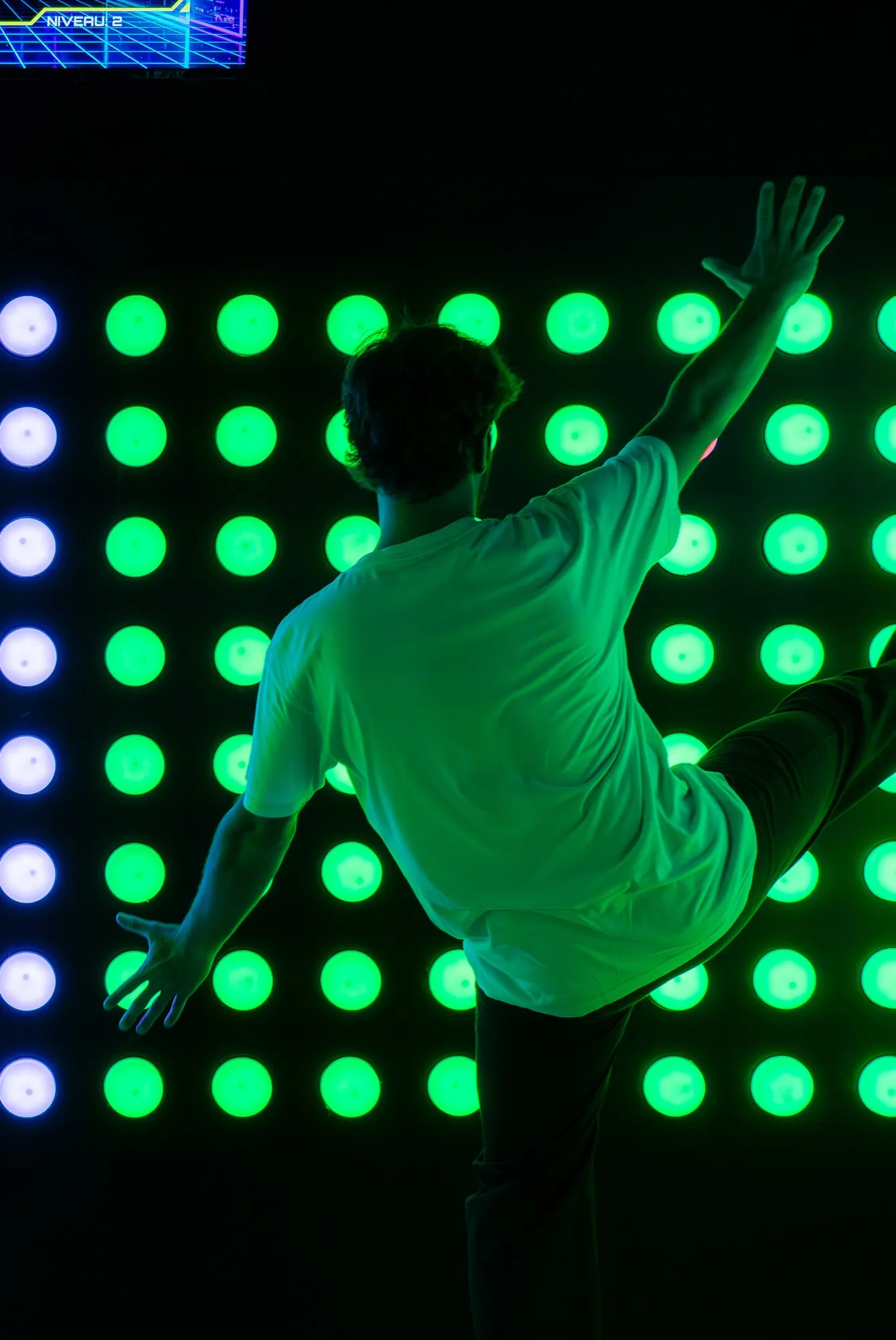 Joueur en plein saut devant le mur de boutons PUSH ARENA